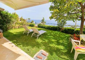 a lawn with chairs and a table and a view of the ocean at Hermes villa Possidi in Possidi +21 photos