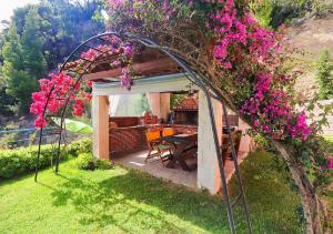 a gazebo with a table and some pink flowers at Hermes villa Possidi in Possidi