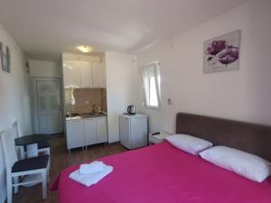 a bedroom with a pink bed and a kitchen at Apartments Luna in Bar