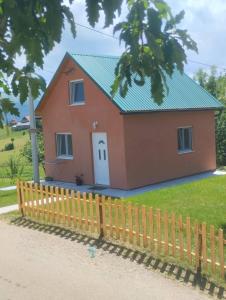 a red house with a green roof behind a fence at Apartment Pivljanka in Pluzine