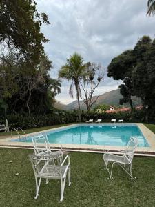 ペトロポリスにあるVilla do Lago Nogueiraのスイミングプール(椅子2脚、テーブル付)