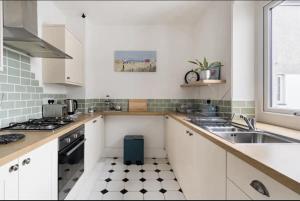 eine weiße Küche mit Spüle und Herd in der Unterkunft Beautiful Sea Front Cottage in the Ocean City in Plymouth + 21 Fotos