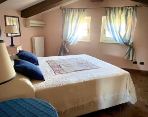 a bedroom with a bed with blue pillows and windows at Locanda del Glis glis in Castelletto d'Orba