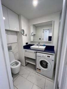 a bathroom with a sink and a washing machine at Orbi City Sea View - Special Category in Batumi +32 photos