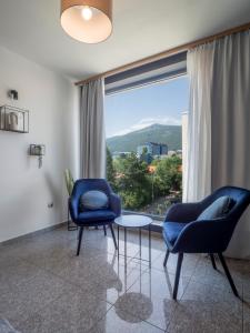 a living room with two chairs and a table and a large window at Vertigo 2 Modern 2-Bedroom Apartment with Parking & Vitosha View in Sofia