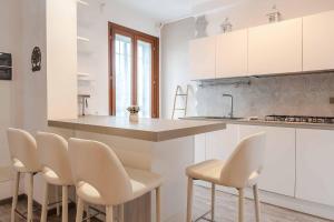 a kitchen with white cabinets and white stools at Residenza l'Ulivo in Foiano della Chiana +18 photos
