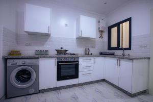 a white kitchen with a washing machine in it at Abali Apartments in Aït Moussa Ou Amar