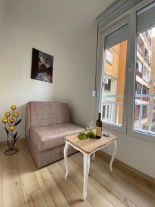 a living room with a couch and a table with a bottle of wine at Comfort studio Lepa Kata in Podgorica
