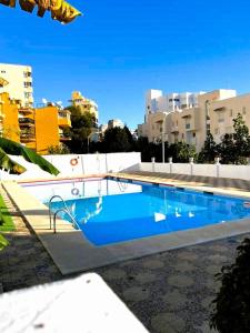 ein großer blauer Pool mit Gebäuden im Hintergrund in der Unterkunft Apartamento Las Mercedes - Playa in Torremolinos