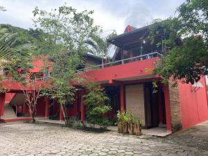 ein rotes Gebäude mit einem Balkon darauf in der Unterkunft Flores do Mar in Arraial d'Ajuda