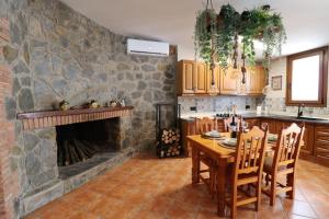 a kitchen with a table and a stone fireplace at La Porteria in Viladomíu Vella