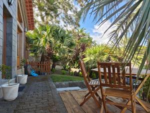 un patio con 2 sedie, un tavolo e palme di Casca de Noz - Modern Rustic Beach Getaway ad Angra do Heroísmo