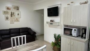 a living room with a couch and a microwave at Residencial Costa Marfim in Bombinhas