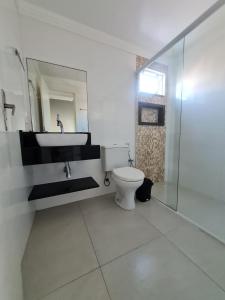 ein Badezimmer mit Toilette, Waschbecken und Spiegel in der Unterkunft Residencial Costa Marfim in Bombinhas