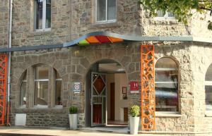a building with an open door with a rainbow at Hôtel de Perros, The Originals Boutique in Perros-Guirec
