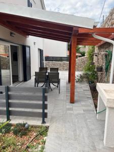 a wooden pergola with a table and chairs on a patio at Apartman Linda in Cres