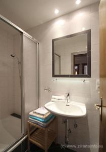 a bathroom with a sink and a shower and a mirror at Ferienwohnungen Hell in Uderns