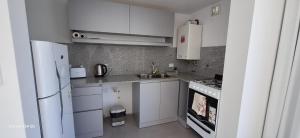 a kitchen with white cabinets and a white refrigerator at Amanecerpuertomadryn 1 in Puerto Madryn +4 photos