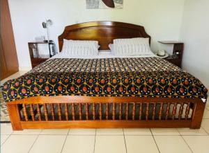 a bedroom with a wooden bed with a blanket on it at Room Vision City 2020 in Kigali