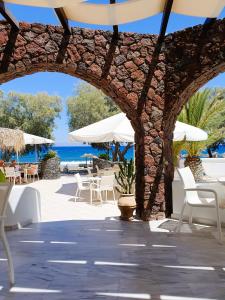 a stone archway with chairs and tables and the ocean at Arion Bay Hotel Santorini in Kamari