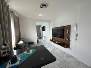 a white living room with a couch and a tv at Apartamento Paraíso da Ilha Porchat ! *Novíssimo!* in São Vicente
