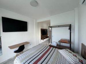a bedroom with a bed and a desk and a television at Apartamento Paraíso da Ilha Porchat ! *Novíssimo!* in São Vicente
