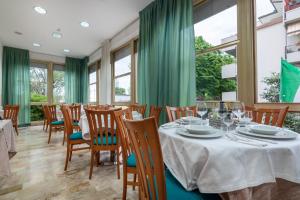 a dining room with a table and chairs and windows at Hotel Ilde in Rimini