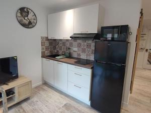 a kitchen with a black refrigerator and white cabinets at T1 - Bord de Mer in Six-Fours-les-Plages +7 photos