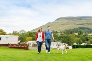a man and a woman walking across a grassy field at Campsie Glen Holiday Park in Fintry