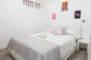 una camera bianca con letto bianco e cuscini rosa di Hogar en Calle Lavapiés a Madrid