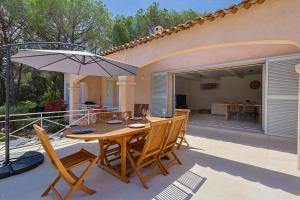 a wooden table with chairs and an umbrella on a patio at Villa avec piscine in Plan-de-la-Tour