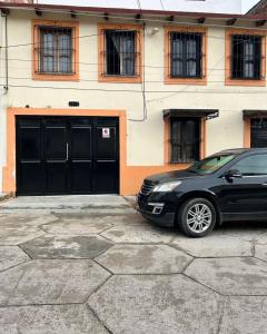un'auto nera parcheggiata davanti a un edificio di Casa De Liz a San Cristóbal de Las Casas