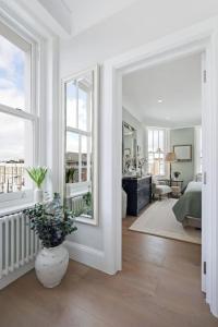 a white living room with a vase with a plant in it at 3 Bed Corner House Portobello Rd in London