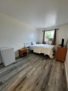 a bedroom with a bed and a desk and a window at Vivian Motor Hotel in Neepawa