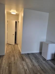 an empty room with a white wall and wooden floors at Vivian Motor Hotel in Neepawa