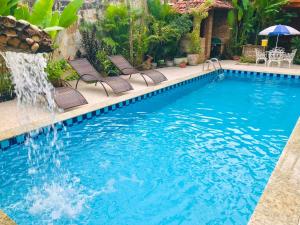 a swimming pool with chairs and a fountain at Terra do Sol Pousada e Hostel in Porto Seguro