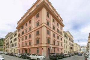un grand bâtiment rose avec des voitures garées devant lui dans l'établissement WWB Colosseo, à Rome