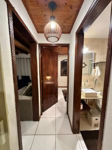 een hal die leidt naar een badkamer met een wastafel en een spiegel bij Residencial Casuarina Monte Verde in Camanducaia +16 foto's