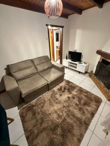 een woonkamer met een bank en een open haard bij Residencial Casuarina Monte Verde in Camanducaia