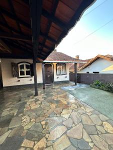 een huis met een stenen terras met een houten dak bij Residencial Casuarina Monte Verde in Camanducaia