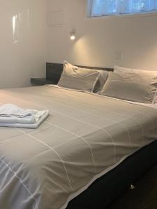 a large white bed with white sheets and pillows at BIG4 Seymour Holiday Park in Seymour