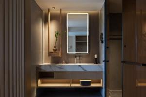a bathroom with a sink and a mirror at Yanyu Yunxi Resort Hotel 烟雨云兮酒店 in Fenghuang County