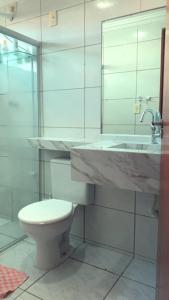 a bathroom with a toilet and a sink and a mirror at Casa de praia in Cabedelo