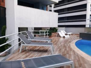 a balcony with chairs and a pool on a building at Flat Atlântico Meireles by Escala in Fortaleza