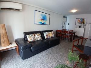 a living room with a black couch and a table at Flat Atlântico Meireles by Escala in Fortaleza