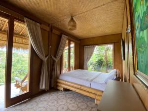 a bedroom with a bed and a large window at Lembah Cinta Mayungan in Baturiti