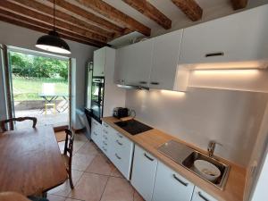 a kitchen with white cabinets and a sink and a table at Retraite Champêtre avec Home Cinéma et Verger Libre Cueillette, près de la Loire et des Châteaux - FR-1-590-435 in Gémigny +13 photos
