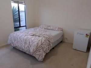 a small bedroom with a bed and a small refrigerator at Budget Ceduna Homestay in Ceduna