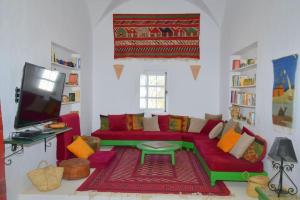 un salon avec un canapé rouge et une télévision dans l'établissement Houch Dar Mami, à Midoun