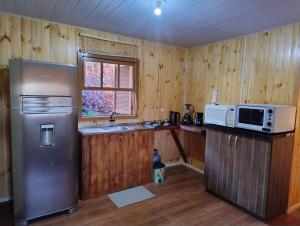 a kitchen with a refrigerator and a microwave at Chalé romântico com vista e banheira in Nova Petrópolis